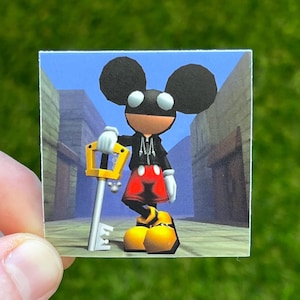May include: A square sticker featuring a cartoon character with large black ears, a black jacket, red shorts, and yellow shoes. The character is holding a gold key and standing in a street scene.