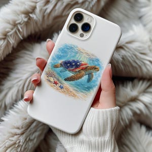 Op de afbeelding: Witte telefoonhoes met een zeeschildpadontwerp, de schild met het Amerikaanse vlagpatroon versierd. De schildpad zwemt in blauw water, met een zandbodem en zeesterren. De hoes heeft een glanzende afwerking.