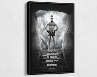 May include: Black and white framed print featuring a muscular person standing on steps with a cloudy background. The print includes the text "Losers focus on winners. Winners focus on winning." and the name "Conor McGregor."