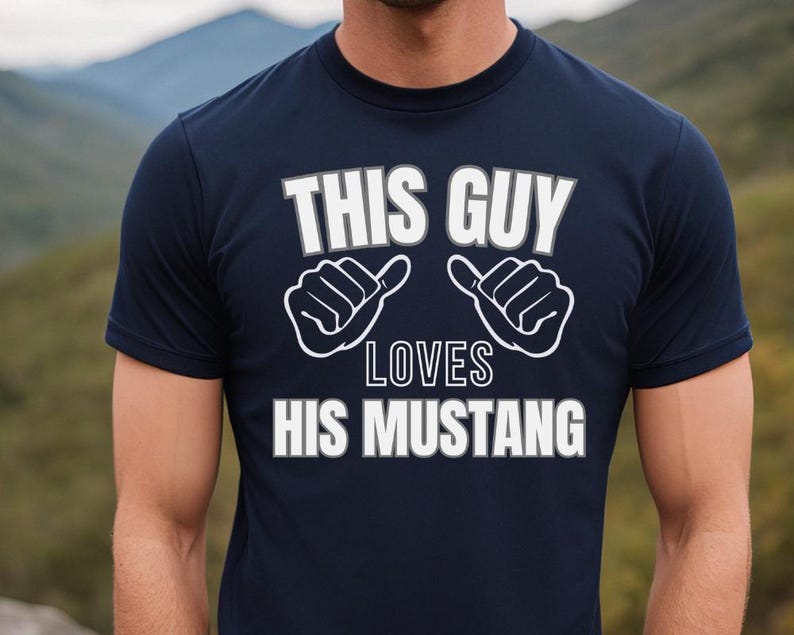 May include: A navy blue t-shirt with white text that reads "This Guy Loves His Mustang". The text is surrounded by two white thumbs up symbols.