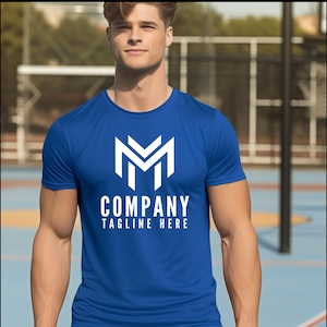 May include: A bright blue short-sleeved t-shirt featuring a large white geometric logo of the letter M on the chest. Below the logo, the text COMPANY is printed in white capital letters, followed by the text TAGLINE HERE in smaller white letters.