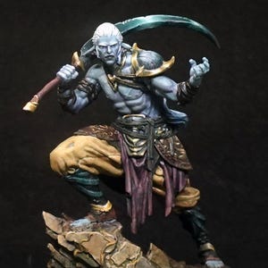 Puede incluir: Figura de fantasía en miniatura de un guerrero con piel azul pálido, cabello blanco y orejas puntiagudas. El guerrero posa con una hoja curva, viste armadura dorada y ropa marrón y morada, de pie sobre una base rocosa.