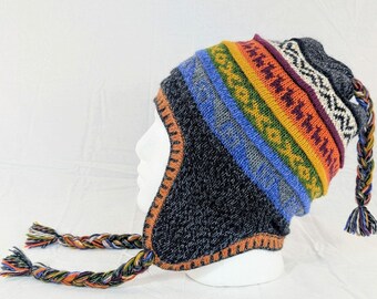 May include: A colorful knit hat with ear flaps and braided tassels. The hat features a dark blue base with a striped pattern of blue, green, yellow, orange, and purple. The ear flaps and tassels are multi-colored.