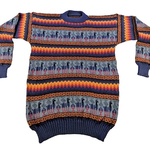 Könnte beinhalten: Ein langärmliger Pullover mit Rundhalsausschnitt und farbenfrohem Muster. Der Pullover hat ein blaues, orangefarbenes und rotes Design mit sich wiederholenden Lamafiguren. Die Manschetten und der Saum sind einfarbig blau. Der Pullover ist aus weichem Strickmaterial.