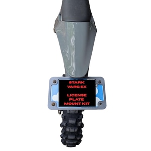 Puede incluir: Sección trasera de una motocicleta con guardabarros gris, neumático negro y kit de montaje de placa de matrícula. El kit de montaje de la placa tiene el texto "STARK VARG EX LICENSE PLATE MOUNT KIT" en rojo.