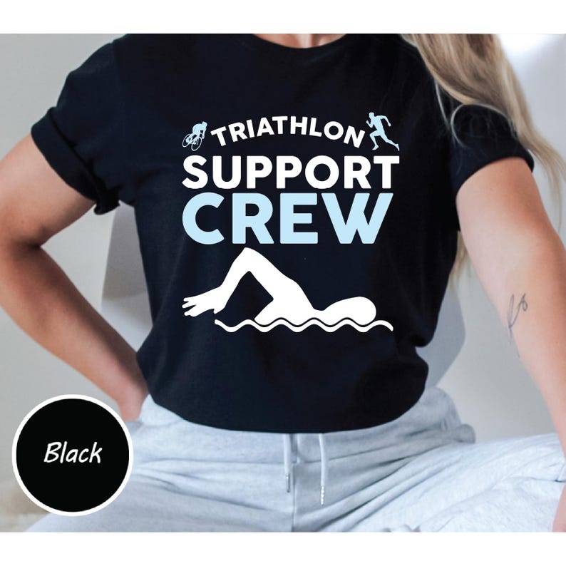 May include: Black t-shirt with the text "TRIATHLON SUPPORT CREW" in white and light blue. The design includes a cyclist, a runner, and a swimmer. A black circle with the word "Black" is in the lower left corner.
