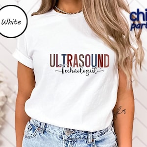 May include: White t-shirt with the words "ULTRASOUND TECHNOLOGIST" in a red, blue, and black design. The shirt has a crew neck and short sleeves. The word "White" is in a black circle in the upper left corner.