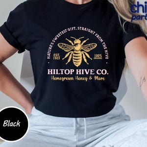 Könnte beinhalten: Schwarzes T-Shirt mit einer detaillierten Bienenillustration und dem Text "HILTOP HIVE CO. Homegrown Honey & More." Das Design enthält die Sätze "Nature's Sweetest Gift, Straight From The Hive" und "100% Organic."