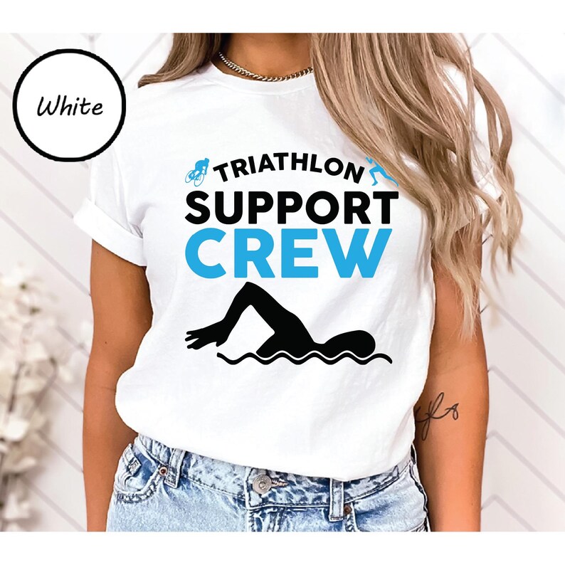 May include: White t-shirt with the words "TRIATHLON SUPPORT CREW" in black and blue. A black silhouette of a swimmer is at the bottom. The word "White" is in a black circle in the upper left corner.