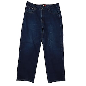 May include: Dark wash denim jeans with a classic five-pocket design. The jeans feature a button and zip closure, belt loops, and the Tommy Hilfiger logo on the front pocket. The jeans have a relaxed fit and are made of a durable denim material.