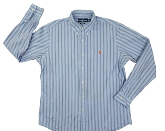Op de afbeelding: Lichtblauw overhemd met verticale strepen in verschillende blauwtinten. Het shirt met lange mouwen heeft een button-down kraag en een klein oranje logo op de borst. Gemaakt van lichtgewicht stof.