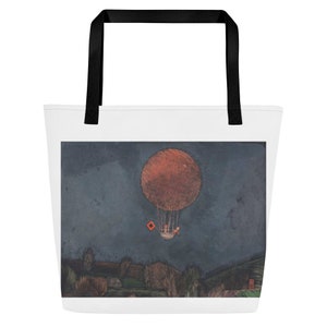 May include: A tote bag featuring a painting of a hot air balloon with two figures inside, flying over a landscape with a red square in the sky. The background is a dark blue color.