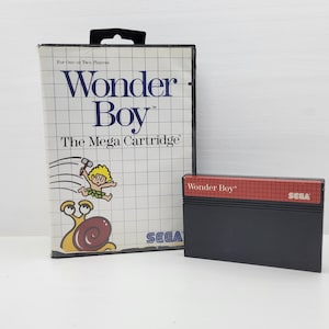 May include: A vintage "Wonder Boy" video game for the Sega Genesis. The box features the game title, a cartoon character, and a snail. The black cartridge is next to the box. The box and cartridge are on a white surface.