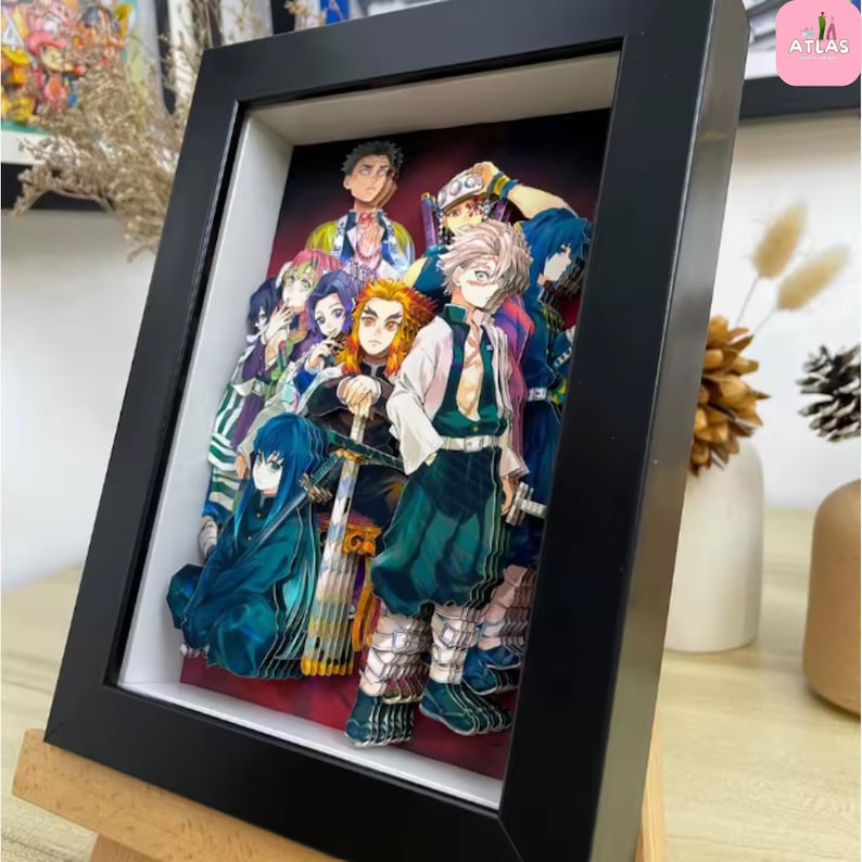 May include: A framed 3D artwork featuring a group of anime characters. The artwork is encased in a black frame with a white interior, creating a layered effect. The characters are depicted in vibrant colors, with detailed clothing and expressions.
