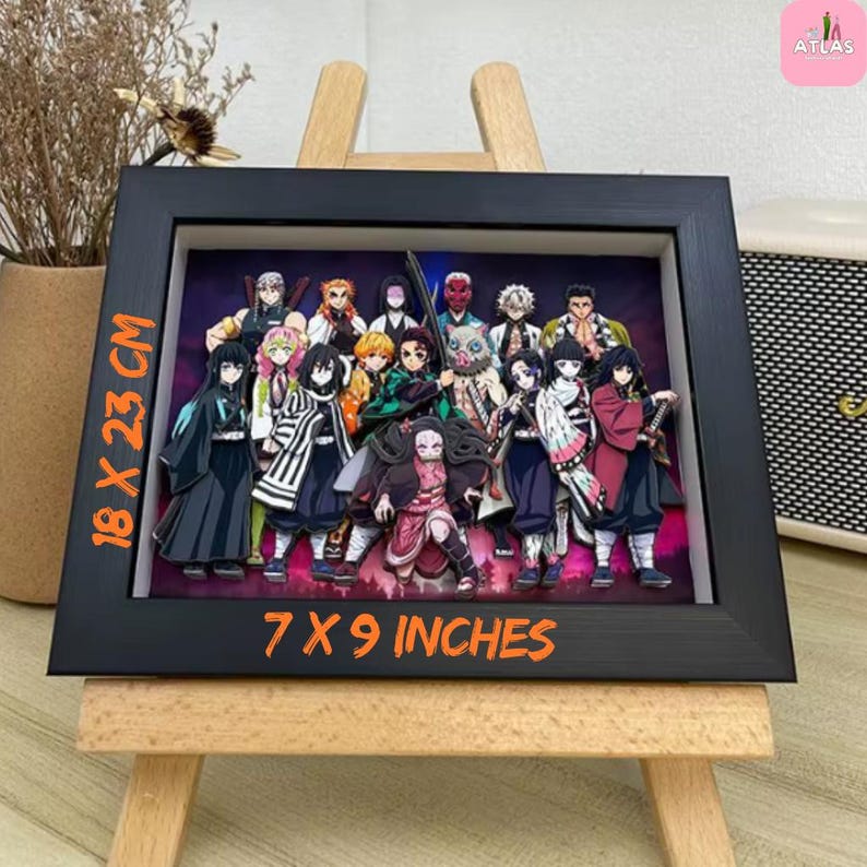 May include: A framed artwork featuring a group of anime characters. The black frame measures 7 x 9 inches and displays a colorful illustration of various figures. The artwork is displayed on a small wooden easel.