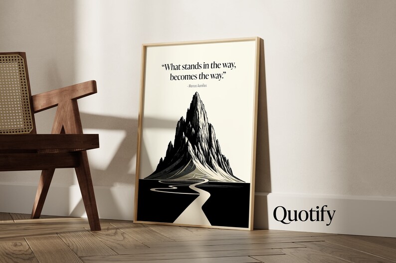May include: A framed black and white illustration of a mountain with a winding road leading to the peak. The quote "What stands in the way, becomes the way." by Marcus Aurelius is printed below the image. The word "Quotify" is printed in black at the bottom right corner of the image.