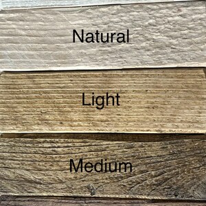 Op de afbeelding: Vijf houten planken die in verschillende bruintinten zijn gebeitst. De planken zijn van licht naar donker gelabeld: Witte tint, Natuurlijk, Licht, Medium, Donker.