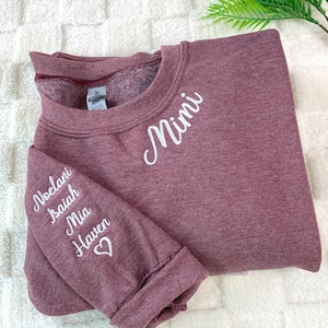 以下が含まれることがあります： 白の刺繍文字が入ったマルーン色のスウェットシャツ。「Mimi」の文字が胸に刺繍されています。左袖には「Noelani Isaiah Mia Haven」という名前が白で刺繍されており、ハートのマークが付いています。