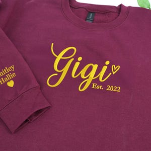 Maroon embroidered sweatshirt featuring "Gigi EST. 2022" with a heart. Personalized grandma sweatshirt gift for Mother’s Day, Christmas, or birthdays. Cozy vintage-washed fabric perfect for proud grandmothers celebrating their family legacy.