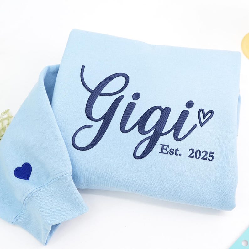 Light Blue embroidered sweatshirt featuring "Gigi EST. 2025" with a heart. Personalized grandma sweatshirt gift for Mother’s Day, Christmas, or birthdays. Cozy vintage-washed fabric perfect for proud grandmothers celebrating their family legacy.