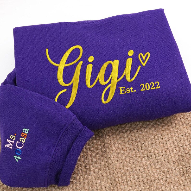 Purple embroidered sweatshirt featuring "Gigi EST. 2022" with a heart. Personalized grandma sweatshirt gift for Mother’s Day, Christmas, or birthdays. Cozy vintage-washed fabric perfect for proud grandmothers celebrating their family legacy.
