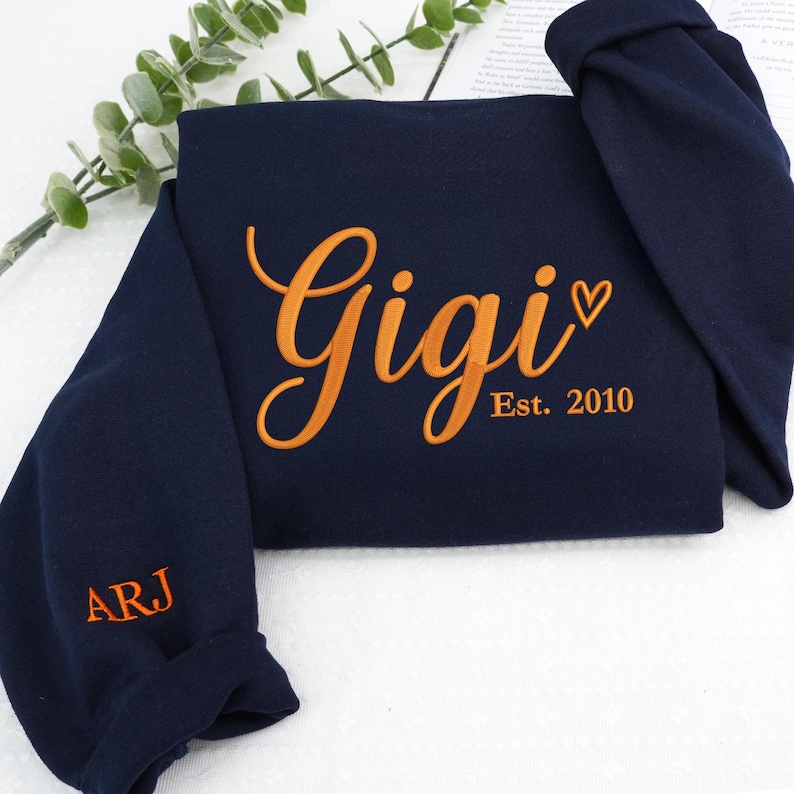 Navy embroidered sweatshirt featuring "Gigi EST. 2010" with a heart. Personalized grandma sweatshirt gift for Mother’s Day, Christmas, or birthdays. Cozy vintage-washed fabric perfect for proud grandmothers celebrating their family legacy.