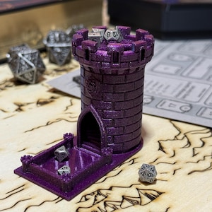 May include: A purple dice tower with a castle design. The tower has a cylindrical body with a crenelated top and an arched opening. Several dice are visible in the tray and on top of the tower. The tower is designed for tabletop gaming.