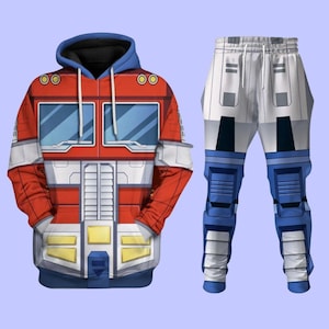Könnte beinhalten: Ein rotes, weißes und blaues Hoodie- und Hosen-Set. Der Hoodie zeigt ein Design, das der Brust eines Roboters ähnelt, mit blauen fensterartigen Details. Die Hose ist weiß mit blauen und grauen Akzenten.