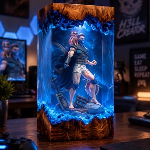 May include: A rectangular resin and wood lamp featuring a central figurine of a character wearing a black vest, cape, and heart-patterned boxers, with a small animal on their shoulder, illuminated by internal blue LED lights within the resin.