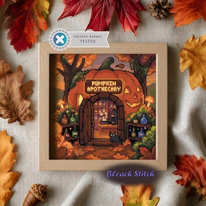 May include: A square wooden frame containing a pixel art cross stitch pattern titled Pumpkin Apothecary. The image depicts a large orange pumpkin building with an open door, a black cat, and shelves of colorful potion bottles inside.