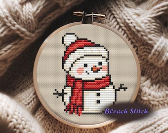May include: Cross-stitch embroidery of a snowman wearing a red and white hat and scarf, with a carrot nose and twig arms. The embroidery is set in a wooden hoop, with the text "Bleach Stitch".