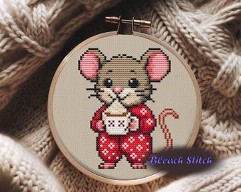 May include: Cross-stitch embroidery of a cartoon mouse wearing red pajamas with white snowflake patterns, holding a mug of coffee with whipped cream. The mouse has brown fur, pink ears, and a pink nose. The embroidery is in a wooden hoop, with the text "Bleach Stitch".