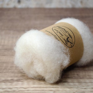 May include: A white roll of wool fiber, wrapped in brown paper with a label that reads "South Star" and a website address.