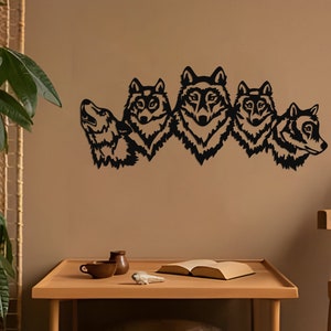 Puede incluir: Arte de pared de metal negro con cinco cabezas de lobo de perfil, dispuestas en fila. Las cabezas de lobo están mirando hacia adelante, con la boca abierta y los dientes visibles. El arte de pared está montado en una pared marrón.