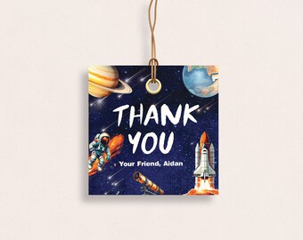 May include: A blue and black space-themed thank you tag with a rocket, astronaut, planets, and stars. The text reads "Thank You, Your Friend, Aidan".