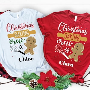 May include: Two Christmas-themed t-shirts, one white and one red, with the text "Christmas BAKING crew". Each shirt features a rolling pin, gingerbread man, whisk, and snowflake graphic. The white shirt says "Chloe" and the red shirt says "Clara".