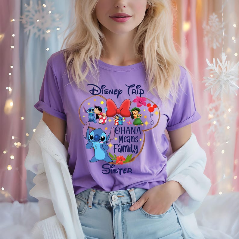 May include: A lilac-colored t-shirt featuring a Disney-themed graphic. The design includes the text "Disney Trip" and "Ohana Means Family Sister" along with cartoon characters and a red bow. The shirt has rolled-up sleeves.