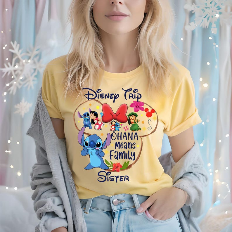 May include: Yellow t-shirt featuring a Disney Trip design with Stitch and other characters. The design includes the text "Ohana Means Family Sister" in a playful font. The shirt is a short-sleeved crew neck.