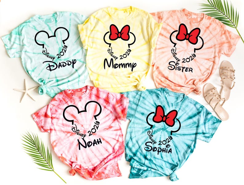 Pu&ograve; includere: Magliette tie-dye in tonalit&agrave; blu, giallo, rosa e pesca. Ogni maglietta presenta un design a forma di testa di Topolino o Minnie con la scritta "Disney 2020" e il nome di un familiare, come "Daddy" o "Mommy".
