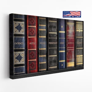 May include: A framed canvas print featuring a row of books with motivational words. The books are in various colors, including blue, red, and gold, with words like "Patience" and "Hustle" visible. The print includes a "Made in USA" label.
