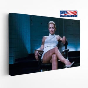 May include: A canvas print featuring a woman in a white dress and heels, seated in a black chair. The image has a blue-toned background and a "Made in USA" sticker.