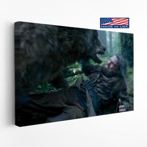 May include: A canvas print depicting a dramatic scene of a man in a brown outfit being attacked by a large wolf in a forest setting. The print has a "Made in USA" label.