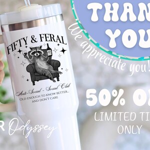 May include: White insulated tumbler with a handle, featuring a raccoon illustration holding a wine glass and bottle, with the text "FIFTY & FERAL" and "Anti-Social - Social Club". The tumbler also has the text "THANK YOU" and "50% OFF".
