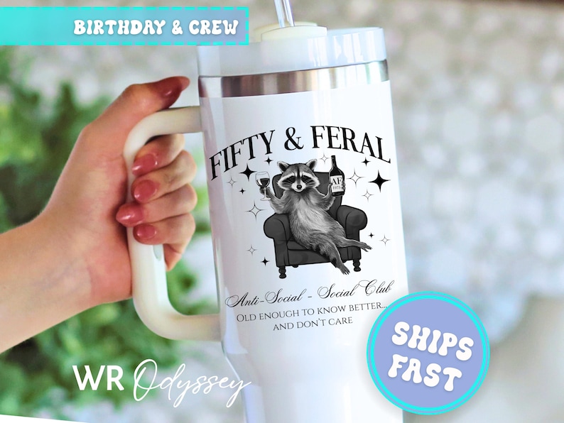 May include: White insulated tumbler with a handle, featuring a raccoon illustration holding a wine glass and bottle. Text reads "FIFTY & FERAL" and "Anti-Social - Social Club". Includes a straw and a lid. The tumbler is approximately 10 inches tall.