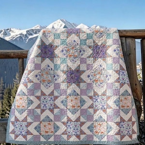 Puede incluir: Una colcha de patchwork con un patrón de estrellas repetitivo en tonos lavanda, verde azulado y crema. Los bloques de tela muestran intrincados motivos florales y animales, con costuras visibles en toda la superficie textil, creando un diseño geométrico.