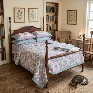 May include: A wooden four-poster bed features a quilt and two matching pillows with a lavender and blue star-patterned floral design. The bedding set includes a folded quilt at the foot of the bed, all resting on a dark wood frame in a room.