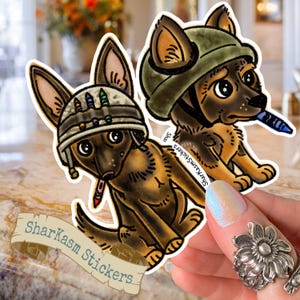 Peut inclure: Deux autocollants représentant des chiots de berger allemand de dessin animé portant des casques militaires et tenant des crayons. Les chiots sont bruns et noirs. Un casque est vert olive, l'autre est beige avec des détails colorés. Les autocollants ont le texte "Sharkasm Stickers".