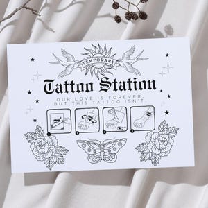 Puede incluir: Ilustraci&oacute;n en blanco y negro de una estaci&oacute;n de tatuajes temporales con un dise&ntilde;o de sol y p&aacute;jaros. El texto dice "Temporary Tattoo Station. Our love is forever, but this tattoo isn't."