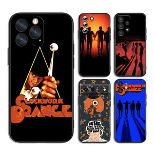 Può includere: Cinque cover nere per smartphone con immagini del film A Clockwork Orange. I design includono sagome di quattro figure su sfondi arancioni e blu, un primo piano con un bastone con un occhio e una cover a motivi decorativi con del testo.