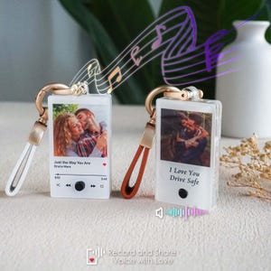 May include: Two clear acrylic keychains with photos and music player designs. The keychain on the left has a photo of a couple and the text "Just the Way You Are" by Bruno Mars. The keychain on the right has a photo of a couple and the text "I Love You Drive Safe".